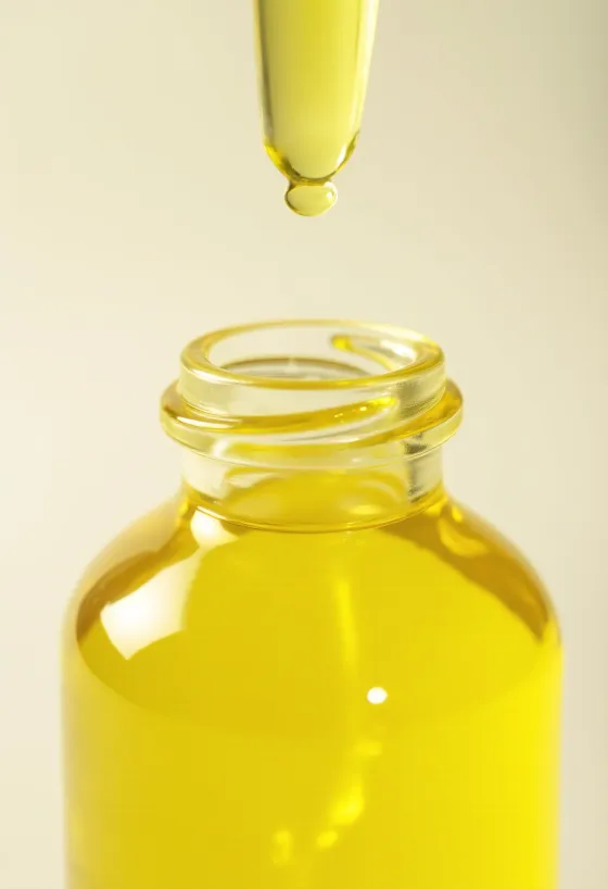 زيت الليمون في زجاجة صغيرة بجانب شرائح ليمون طازجة وقشر مبشور