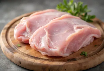 قطع لحم ديك رومي طازجة مع بهارات وثوم على لوح خشبي