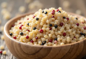 حبوب كينوا نيئة مختلطة الألوان في وعاء وعلى سطح خشبي